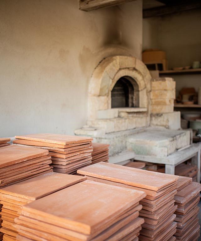 Piastrelle in terracotta accatastate vicino a un forno artigianale in Puglia